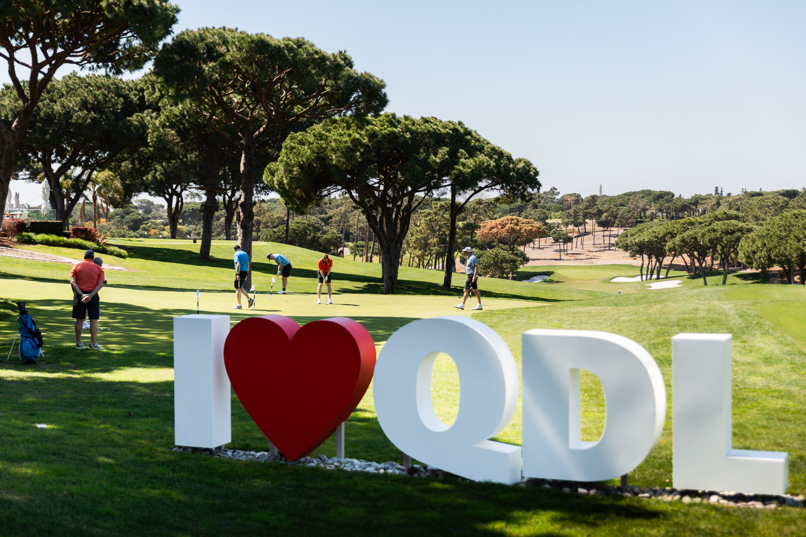 Living in Portugal Guide featuring a refined Algarve lifestyle scene with golfers on a pristine green at Quinta do Lago.