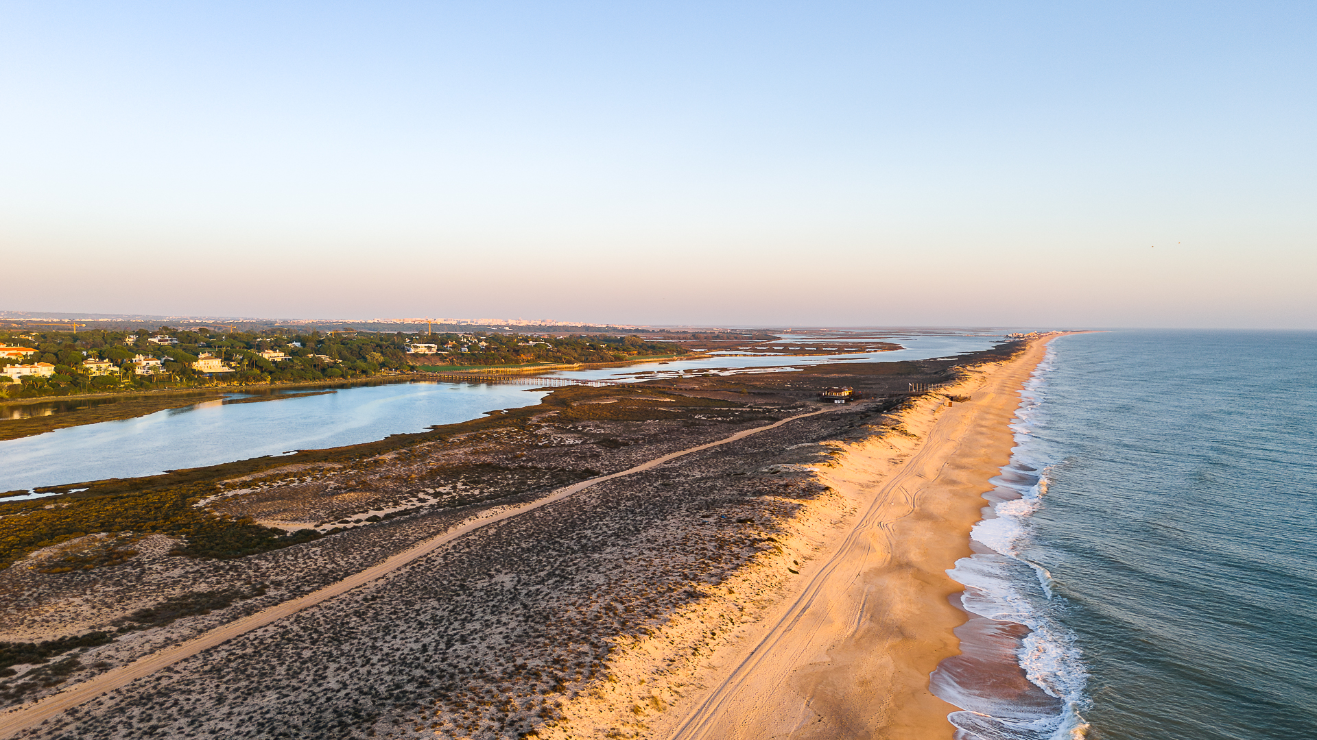 Portugal Beachfront Real Estate featuring an aerial view of a long sandy coastline, Atlantic waters, and sunlit dunes in Portugal.